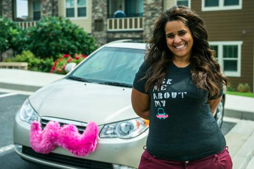 Chris Detrick  |  The Salt Lake Tribune
Angie Palmer poses for a portrait with her car in Midvale Thursday August 7, 2014.  Salt Lake City is issuing $6,500 tickets to drivers for the ridesharing services Lyft and Uber, contending they essentially are illegal taxi operations.