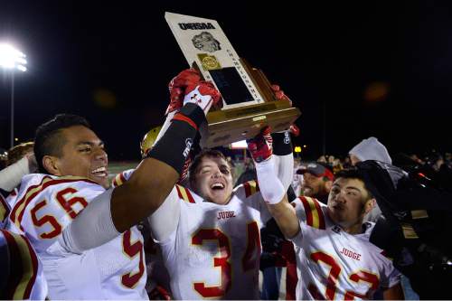 Scott Sommerdorf  |  The Salt Lake Tribune
Patrick Maka, left, star RB Maxwell Barnett, and Michael Kearns celebrate with the 3A trophy after Judge defeated Juab 63-14 for the state 3A championship in Cedar City, Friday, November 14, 2014.