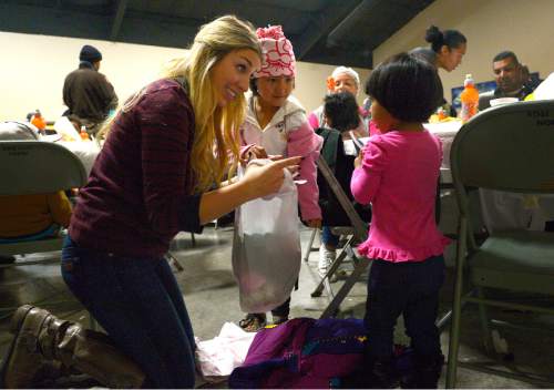 Leah Hogsten  |  The Salt Lake Tribune
l-r Volunteer Bailey High helps sisters Emily Lilo, 5,  and Grecia Lilo, 1, pack up their new clothes and toys after their afternoon Thanksgiving meal.  The Salt Lake City Mission provided Thanksgiving meals at the Christian Life Center, Thursday, November 27, 2014 in Salt Lake City.