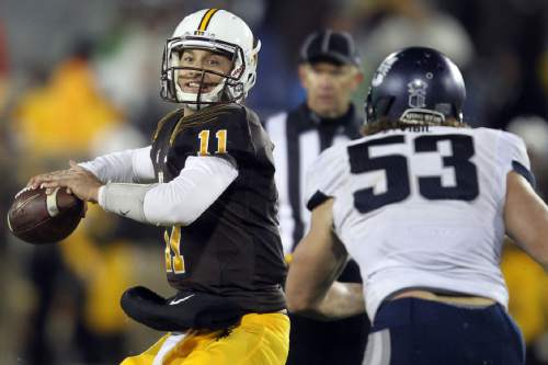 Wyoming quarterback Colby Kirkegaard looks to throw a pass under pressure from Utah State's Zach Vigil during an NCAA college football game Friday, Nov. 7, 2014, in Laramie, Wyo. (AP Photo/Wyoming Tribune Eagle, Miranda Grubbs)