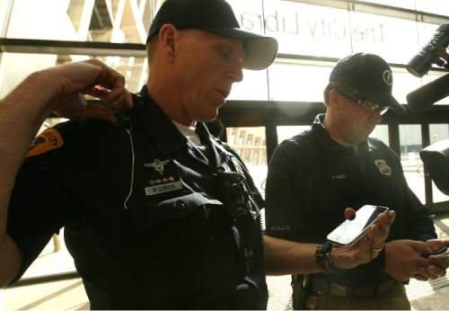 Leah Hogsten  |  The Salt Lake Tribune
In this November 2012 file photo, Salt Lake City police officer Brent Larsen (left) demonstrates how the magnet-attached Axon Flex camera on his collar streams live video to his cell phone. Salt Lake City Police Department unveiled the body camera system in 2012. It allows audio-visual recording of an incident from the officer's perspective. On Thursday, the Department of Public Safety announce that all its officers will wear body cameras.