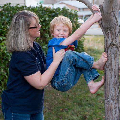 Rick Egan  |  The Salt Lake Tribune

Christy helps her son Sage, 5 climb a tree, Monday, December 8, 2014, Christy's kids  have been receiving Christmas presents through the Prison Fellowship's Angel Tree program, where local churches, businesses and individuals purchase the gifts, which are given to the kids in their parent's name.