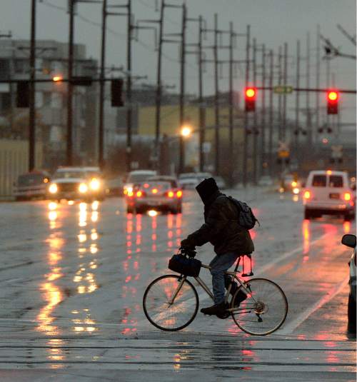 Al Hartmann  |  The Salt Lake Tribune
Bike commuter braves the dark and rain early Monday morning Dec. 22 at 200 W. and 800 S. in Salt Lake City.  The intersection was the scene of a TRAX multiple car accident an hour earlier.