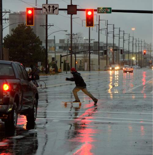 Al Hartmann  |  The Salt Lake Tribune
Skateboarding in the rain in December?  Brave skateboarder crosses 200 W. and 800 S. in a pouring rain at 8 a.m  Monday morning.  The intersection was the scene of a TRAX multiple car accident an hour earlier.