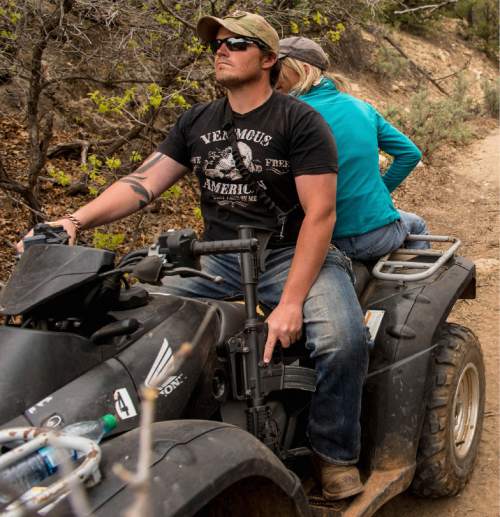 Trent Nelson  |  The Salt Lake Tribune
A rider holds his finger off the trigger of his assault rifle as motorized vehicles make their way through Recapture Canyon on Saturday May 10, 2014. San Juan County Commissioner Phil Lyman, who is facing criminal charges for his role in the ride, says tensions that lead to confrontations can be traced in part to slow-moving federal bureaucracy. The trail was closed "temporarily" in 2007 but remains closed today, he notes.