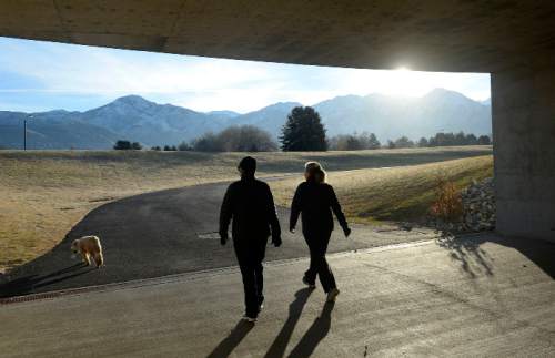 Al Hartmann  |  The Salt Lake Tribune
Walkers step from a tunnel into Sugar House Park as the sun peeks over the mountains for another clear, warm day on Wednesday. Get set for a change on Christmas Day with colder temperatures and snow expected in the valley.
