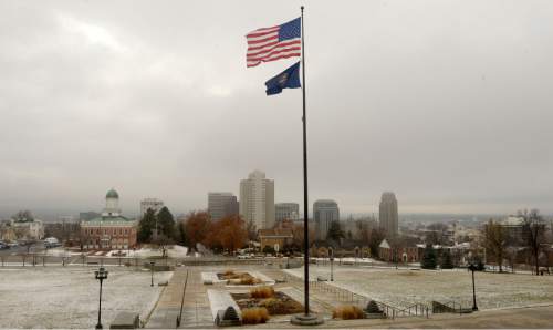 Al Hartmann  |  The Salt Lake Tribune
The American and Utah state flag at the Capitol flutter in a moderate westerly breeze Tuesday January 13, 2015, as the city skyline begins to emerge after several days of pollution buildup. Welcome to January weather limbo. Alternating days of storms blow polluted air out of the Salt Lake Valley followed by a build up of stagnant air that allows pm 2.5 to build up again.