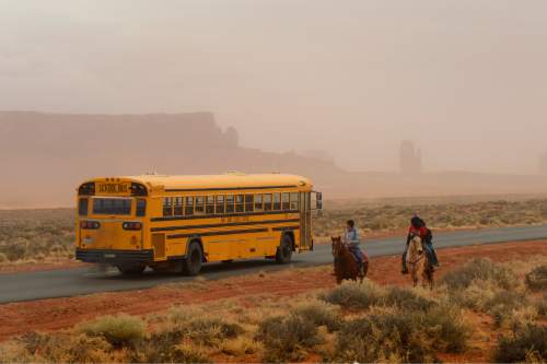 Rick Egan  | The Salt Lake Tribune 

A school bus from Monument Valley High School passes Jaydon Yazzie, VanteJren Atene and McKalette Clark, as they ride home from school on their horses onThursday, January 30, 2014.