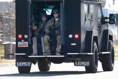 Scott Sommerdorf   |  The Salt Lake Tribune
Officers in an armored vehile drive to the scene where a bank robbery suspect lays handcuffed on the ground as a bomb squad robot attempts to search his vest, Thursday, January 22, 2015. He was arrested and taken away after the robot removed the vest that was suspected of holding an explosive device.