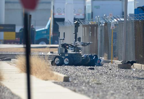 Scott Sommerdorf   |  The Salt Lake Tribune
A bank robbery suspect wearing a motorcycle helmet lies handcuffed on the ground near 1045 West and Jewell Avenue as a bomb squad robot attempts to search his vest, Thursday, Jan. 22, 2015.