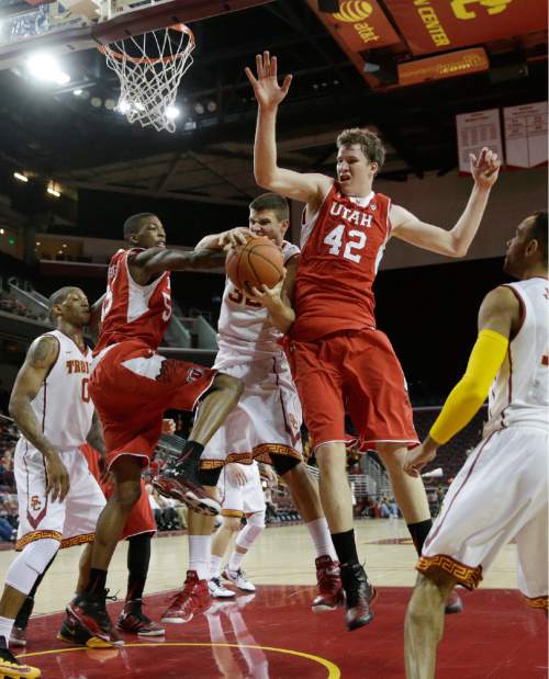 Southern California's Nikola Jovanovic, center, of Serbia, gets a rebound against Utah's Delon Wright, left, and Jakob Poeltl, of Austria, during the first half of an NCAA college basketball game, Sunday, Feb. 1, 2015, in Los Angeles. (AP Photo/Jae C. Hong)