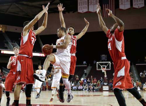 Southern California's Chass Bryan, center, passes the ball as he is defended by Utah's Kyle Kuzma, left, Brandon Taylor and Dakarai Tucker, right, during the second half of an NCAA college basketball game, Sunday, Feb. 1, 2015, in Los Angeles. Utah won 67-39. (AP Photo/Jae C. Hong)