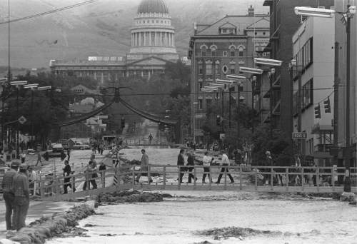 Tribune file photo

Pedestrians use a temporary wooden bridge to cross State Street in Salt Lake City, which County Flood Control Director Terry Holzworth transformed into a river to contain overwhelming runoff from City Creek in June 1983.