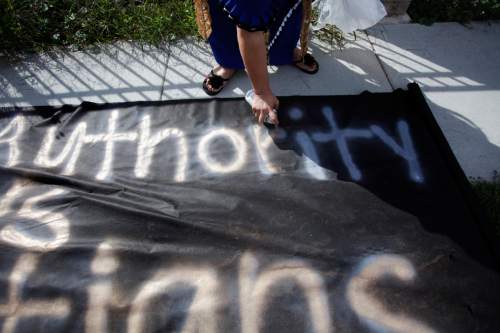 Ashley Detrick  |  The Salt Lake Tribune
Saane Lotaki spray paints a sign that says "Absolute authority misleads true Christians" during a protest at the Tongan United Methodist Church on Sept. 23, 2012.  Members of the West Valley City church were upset that they were not given an explanation for the removal of their pastor, Rev. Filimone Havili Mone, the previous month.
