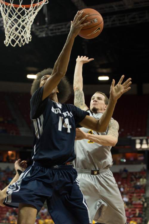 Rick Egan  |  The Salt Lake Tribune

Utah State Aggies guard Jalen Moore (14) goes to the hoop as Wyoming Cowboys guard Josh Adams (14) defends in Mountain West Conference Basketball Championship action, Utah State vs. Wyoming, at the Thomas & Mack Center in Las Vegas, Thursday, March 12, 2015.