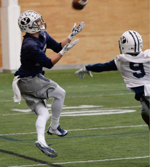 Francisco Kjolseth  |  The Salt Lake Tribune 
BYU's wide receiver Kurt Henderson pull in a pass ahead of defensive back Michael Shelton as  football opens spring camp on Monday, March 2, 2015, with indoor practice at the Smith Fieldhouse.