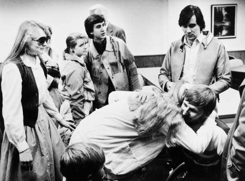 Tribune file photo

John Timothy Singer (seated) gets a hug during a court hearing. Behind him is Addam Swapp.