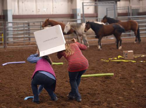 Al Hartmann  |  The Salt Lake Tribune 
Psychotherapy counselors Bernadette Madara and Carissa Palmberg crouch under a box to approach a group of horses at the Equine Assisted Growth and Learning Association 16th annual conference at Legacy Arena in Farmington Thursday March 26, 2015. EAGALA is a Santaquin-based nonprofit, that uses horses in therapy for veterans, couples, at-risk youth, as well as in corporate team building and in personal development.  It can be used with or to replace talk therapy. EAGALA says it has more than 4,500 members in 50 countries in Africa, North America, the Middle East, Latin America and Australia, who are using its techniques.