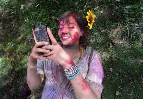 Scott Sommerdorf   |  The Salt Lake Tribune
Ashley Morgan checks photos on her phone on the grass after the second color throw of the day. Thousands celebrated the arrival of Spring at the Sri Sriradha Krishna Temple in Spanish Fork Saturday March 28, 2015. The Holi Festival of Colors continues Sunday from 11 a.m. to 4 p.m.