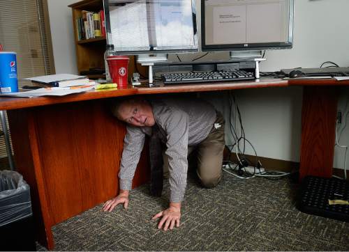 Scott Sommerdorf   |  The Salt Lake Tribune
Rick Hughes, director of Learning, Development and Performance Management for the Utah Department of Human Resources, ducks under his desk and follows the "Stop, Drop and Hold on" protocol. The alarm had just sounded at 10:15 a.m. signaling the beginning of the annual Great Utah ShakeOut earthquake drill at the Utah State Capitol complex, Thursday, April 16, 2015.