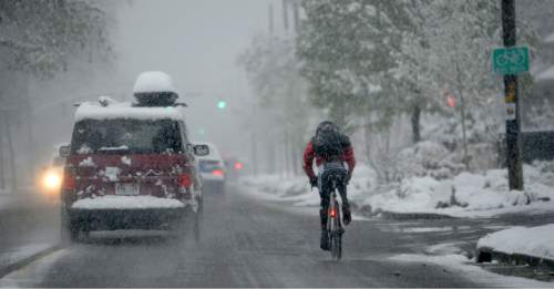 Al Hartmann  |  The Salt Lake Tribune 
Cars and a bicyclist endure a snowy commute Wednesday morning, April 15, 2015.