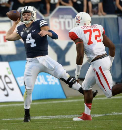Steve Griffin  |  Tribune file photo
BYU Cougars quarterback Taysom Hill (4) throws an off balanced pass as Houston Cougars defensive end Gavin Stansbury closes in during game between BYU and Houston and LaVell Edwards Stadium in Provo, Thursday, September 11, 2014.