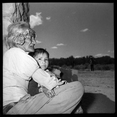 Salt Lake Tribune archive

An elderly Navajo woman holding a child at St. Cristopher's Mission in Bluff, Utah, 1950. St. Christopher's Episcopal Mission was established in 1943 when H. Baxter Liebler, an Episcopal priest from Old Greenwich, Connecticut came to Bluff to establish a mission among the Navajo people. St Christopher's is named after the patron saint of travelers.  When Father Liebler arrived in Bluff, there were no missions, schools, or medical/hospital facilities for the Navajo living in this remote Utah section of the reservation. Before arriving in southeast Utah, Father  Liebler studied the Navajo language to make his message comprehensible to the Dineh and compatible with their understanding of harmony.  He participated in Navajo ceremonies, wore his hair in the traditional Navajo style-long, pulled back and wrapped. A year after the mission was established, a school was started which became the only school for the 1,500 Navajo living in the central part of the Utah strip of the Navajo Reservation. A hospital/ clinic building was completed in 1956.  An estimated 500 babies were born in the clinic during the years it was in operation.