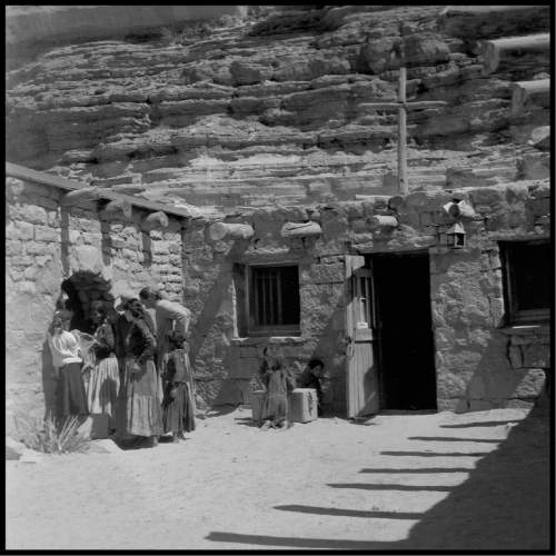 Salt Lake Tribune archive

Father Liebler talks to a group of people outside the chapel at St. Cristopher's Mission in Bluff, Utah, 1950. St. Christopher's Episcopal Mission was established in 1943 when H. Baxter Liebler, an Episcopal priest from Old Greenwich, Connecticut came to Bluff to establish a mission among the Navajo people. St Christopher's is named after the patron saint of travelers.  When Father Liebler arrived in Bluff, there were no missions, schools, or medical/hospital facilities for the Navajo living in this remote Utah section of the reservation. Before arriving in southeast Utah, Father  Liebler studied the Navajo language to make his message comprehensible to the Dineh and compatible with their understanding of harmony.  He participated in Navajo ceremonies, wore his hair in the traditional Navajo style-long, pulled back and wrapped. A year after the mission was established, a school was started which became the only school for the 1,500 Navajo living in the central part of the Utah strip of the Navajo Reservation. A hospital/ clinic building was completed in 1956.  An estimated 500 babies were born in the clinic during the years it was in operation.