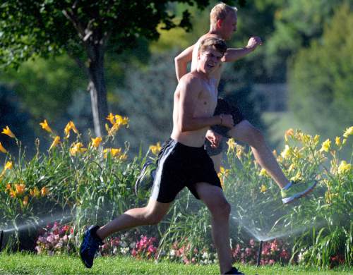 Al Hartmann  |  Tribune file photo 
Runners take advantage of sprinklers to cool down on their training run in Sugar House Park.