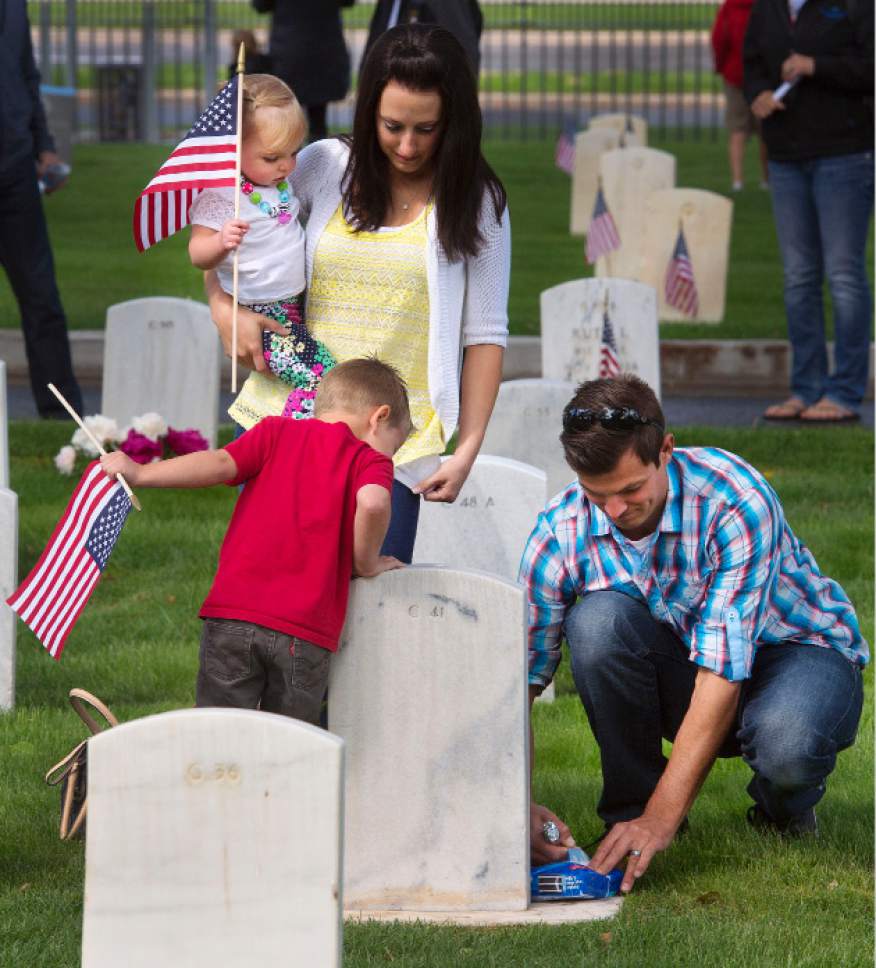 Steve Griffin  |  The Salt Lake Tribune
Becky Clark holds her daughter, Brinley, as her son, Mason, and husband, Jeff, open a package of Oreo cookies at the grave of her father, Air Force Maj. A. Brent Merrill, as Fort Douglas hosts its annual Memorial Day observance at the cemetery in Salt Lake City, Monday, May 25, 2015. Clark, whose father passed away in 1988 of cancer, said her father was a frugal career military man who thought flowers were a waste of money because they just died. So every year the Clarks bring a package of Oreo cookies and a candy bar that they share and leave the rest for grandpa.