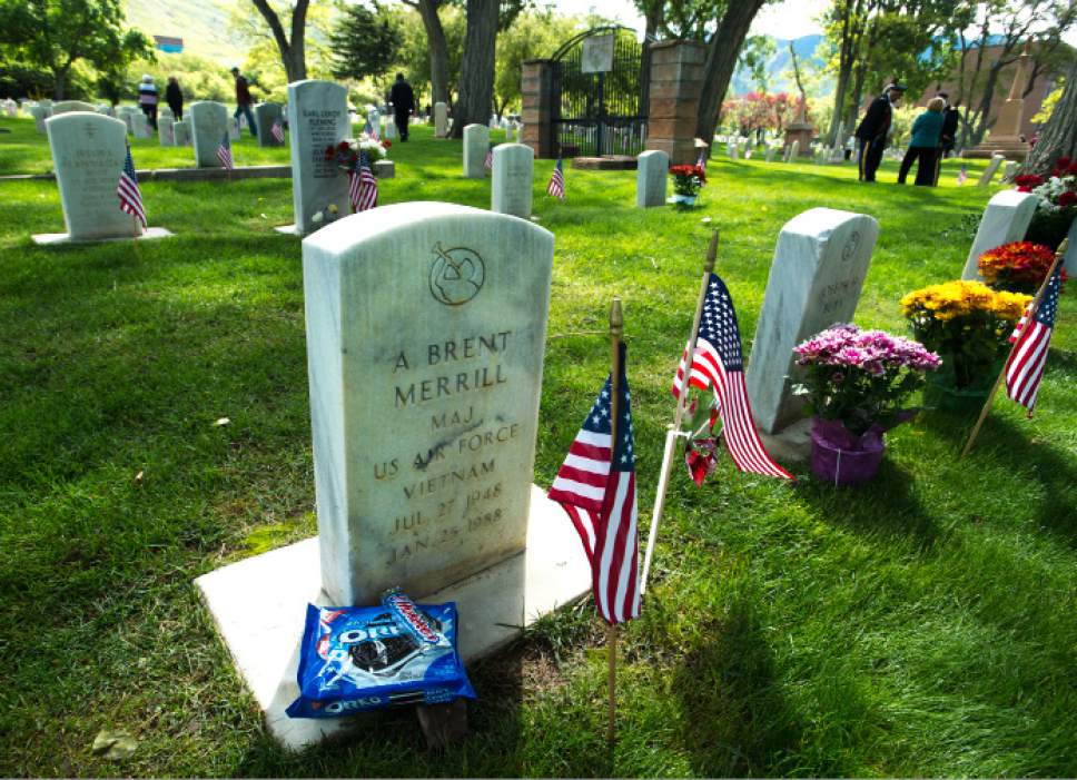 Steve Griffin  |  The Salt Lake Tribune
A candy bar and a partially eaten package of Oreo cookies are left at the grave of Air Force Maj. A. Brent Merrill, as Fort Douglas hosts its annual Memorial Day observance at the cemetery in Salt Lake City, Monday, May 25, 2015. Becky Clark and husband, Jeff, and their children Brinley and Mason eat some of the Oreo cookies at the grave of her father who passed away in 1988 of cancer. Clark said her father was a frugal career military man who thought flowers were a waste of money because they just died. So every year the Clarks bring a package of Oreo cookies and a candy bar that they share and leave the rest for grandpa.