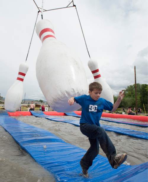 Rick Egan  |  The Salt Lake Tribune

Zeke Sartori, 11, avoids falling in the water as he out-runs the giant bowling pins in the Jugglernaught obstacle in the 5K ThrillSeeker Stunt Run. The run incorporates zip lines, the world's largest inflatable water slide, a Tarzan-like swing and punching walls, at Hee Haw Farms in Pleasant Grove, Saturday, May 23, 2015.