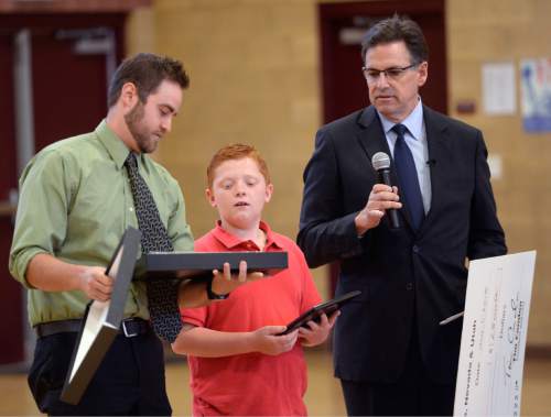 Al Hartmann |  The Salt Lake Tribune
Fifth-grader Brad Mason, accepts a plaque and medal from AAA Utah's Trevor Cole, left, and Scott Jensen, right, holds a $2,500 check for Hawthorn Academy in West Jordan Monday June 2, 2015. Mason accepted the highest award given to a AAA School Safety Patroller, the Lifesaving Medal. He joined an elite group. Only 411 patrollers from around the nation have received this honor since 1949. Past honorees have been U.S. presidents and Supreme Court justices. 
His awareness and quick thinking actions while on duty as a patroller helped save the life of a little girl who was about to run out in front of traffic in front of the school.   He said that he was glad he was paying attention and did as he was trained to do.