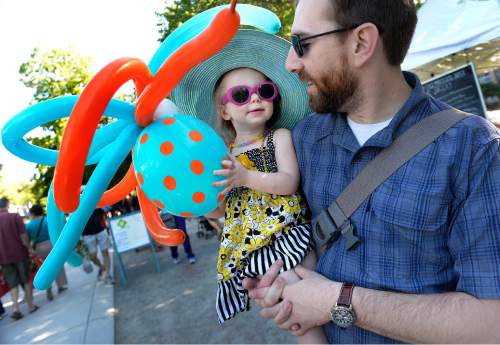 Scott Sommerdorf   |  The Salt Lake Tribune
Josh Anderson holds 2-year-old Amelia, along with her octopus balloon creature, as they make their way through the Downtown Farmers Market as it kicked off its season Saturday, June 13, 2015. Dozens of produce, food, arts and craft vendors will operate each Saturday from 8 a.m. to 2 p.m. through Oct. 24.
