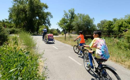 Al Hartmann  |  The Salt Lake Tribune

A family rides their bikes at the intersection of the 9 Line bike trail and Jordan River Parkway at 1000 West and 900 South on June 17, 2015.  A recent survey of Salt Lake City residents about recreation and parks determined that open space parks and bike trails were important to people in the city.