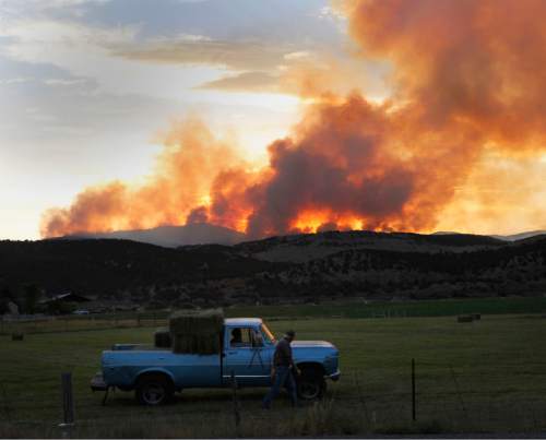 Al Hartmann  |  The Salt Lake Tribune 
Farmer north of Mount Pleasant on Highway 89 keeps working in his alfalfa field past sunset in June as the Wood Hollow fire keeps burning in the mountains several miles to the northwest.