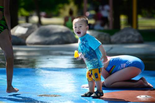 Scott Sommerdorf   |  The Salt Lake Tribune
Two year old Lin Ho plays with his rubber duck at the splash pad water play area inside Liberty Park's Rotary Playground, Monday, June 29, 2015.