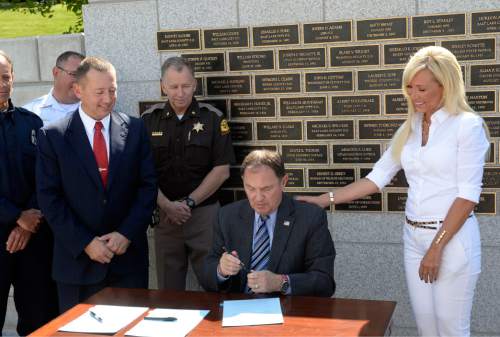 Al Hartmann |  The Salt Lake Tribune
Nannette Wride, widow of slain Utah County Sheriff Sgt. Cory Wride, stands with Gov. Gary Herberts at police memorial outside the Utah Capitol as he signs HB 288, which provides death benefits for Utah peace
officers and firefighters killed in the line of duty.  Rep. Paul Ray, the bill's sponsor, left, with reperesentatives of the police and fire fighting community.