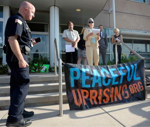 Al Hartmann |  The Salt Lake Tribune
A small group from Peaceful Uprising, Utah Tar Sands Resistance and concerned citizens read statements and performed a skit with children on the steps of the Utah Dept. of Natural Resources as a security guard records them before a crucial hearing Tuesday, June 30 at the Utah Division of Oil, Gas and Mining in Salt Lake City.
