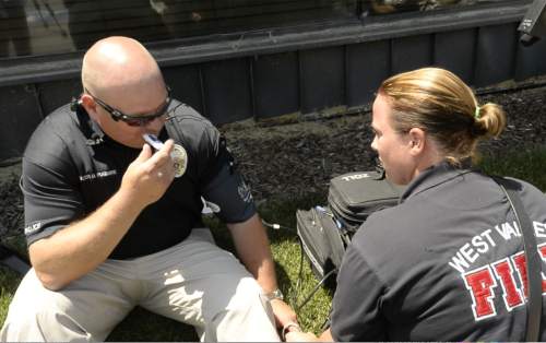 Rick Egan  |  The Salt Lake Tribune

West Valley City Fire Department paramedic Mary Lindsay-Vonk takes police Officer Dana Pugmire's vital signs, before he sat in his car for 15 minutes in the heat of the day during a press conference to illustrate the dangers of leaving children and pets in hot cars, Thursday, July 2, 2015.