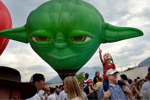 Scott Sommerdorf   |  The Salt Lake Tribune
Five year old Haley Harward rides on her father Steve's shoulders as she looks at all the balloons as they are "standing up" - but after the launch was canceled due to changeable weather, Saturday, July 4, 2015. "Master Yoda" is in the background.