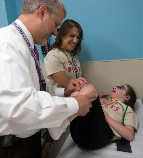 Rick Egan  |  The Salt Lake Tribune
Susan Aragona of Andover, Nj., center, stands by as Alan Stotts, Orthopedic specialist, checks out her 10-year-old daughter, Aniella Aragona, during a special clinic for children with chromosomal disorders at Primary Children's Hospital on Friday. Trisomy is the presence of an extra chromosome.