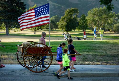 Scott Sommerdorf   |  The Salt Lake Tribune
Families with a hand cart pass golfers near Donner Park during the five-mile commemorative Encampment Hike Saturday, July 18, 2015. The hike, which follows Emigration Creek through Salt Lake City, began at Donner Park and ended at First Encampment Park, near the site where the Mormon pioneers camped in the Salt Lake Valley on July 22, 1847.