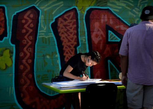 Scott Sommerdorf   |  The Salt Lake Tribune
Liliana Martinex makes signs for supporters to hold outside the Azteca De Oro Taqueria restaurant during the vigil for it's mural of Cesar Chavez and Dolores Huerta on its north wall, Thursday, July 23, 2015.