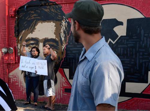Scott Sommerdorf   |  The Salt Lake Tribune
Artist Miguel Galaz, right, turns to see Raymi Gutierrez and James Lemisio raise their hands in support of the mural of Cesar Chavez and Dolores Huerta at the Azteca De Oro Taqueria restaurant, Thursday, July 23, 2015. The pair are holding signs that say "#Art is not a sign" and "#Keep our Murals".