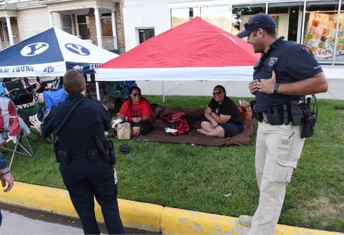 Francisco Kjolseth | The Salt Lake Tribune
Sgt. Lisa Pascadlo and Detective Mason Givens joke around with groups gathered side by side representing the two rival schools while camped out along the Pioneer Day parade route.
