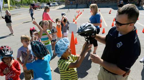 Al Hartmann  |  The Salt Lake Tribune
In celebration of Playin' Safe, the Salt Lake City Police Department and SUBWAY® Restaurants partnered with the Boys & Girls Club of Great Salt Lake to host a safety event on Wednesday, July 28th. Salt Lake City Police officer Richard Chipping gets children from the Boys & Girls Club of Great Salt Lake fitted with bike safety helmets before they take on a bicycle obstacle course to learn safety and the rules of the road.
