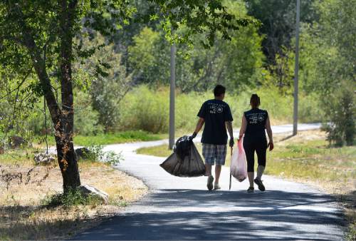 Scott Sommerdorf   |  The Salt Lake Tribune
Volunteers walk along the Jordan River Parkway as they help during the cleanup of the Jordan River. United by Blue hosted a cleanup of the Jordan River in advance of the Outdoor Retailers summer market. The organization pledges to remove one pound of trash from oceans and waterways for every product sold. Volunteers collected 531 pounds of trash.