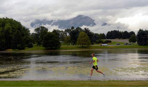 Al Hartmann  |  The Salt Lake Tribune
Cross country runners train in unusual cool rainy weather Monday August 3 at Sugarhouse Park.  Storm clouds hang heavy over the Wasatch Mountains to the east.