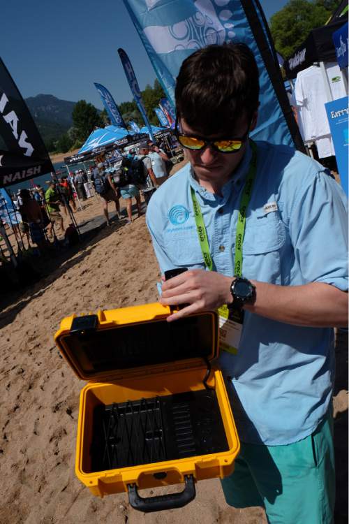Francisco Kjolseth | The Salt Lake Tribune
Jonathan Maki of Drytunes Waterproof Speakers shows off the waterproof case that has a speaker built in to the case and can be controlled from the outside. The Outdoor Retailer Summer Market kicked off with demo day at Pineview Reservoir's Cemetery Point in Huntsville on Tuesday, Aug. 4, 2015. Many of the manufacturers who will be at Summer Market use the opportunity to let retailers try their products, from paddle boards, canoes, kayaks and other water recreation gear.